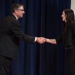 Doctor Smart shaking hands with an award recipeint in a long sleeved black shirt